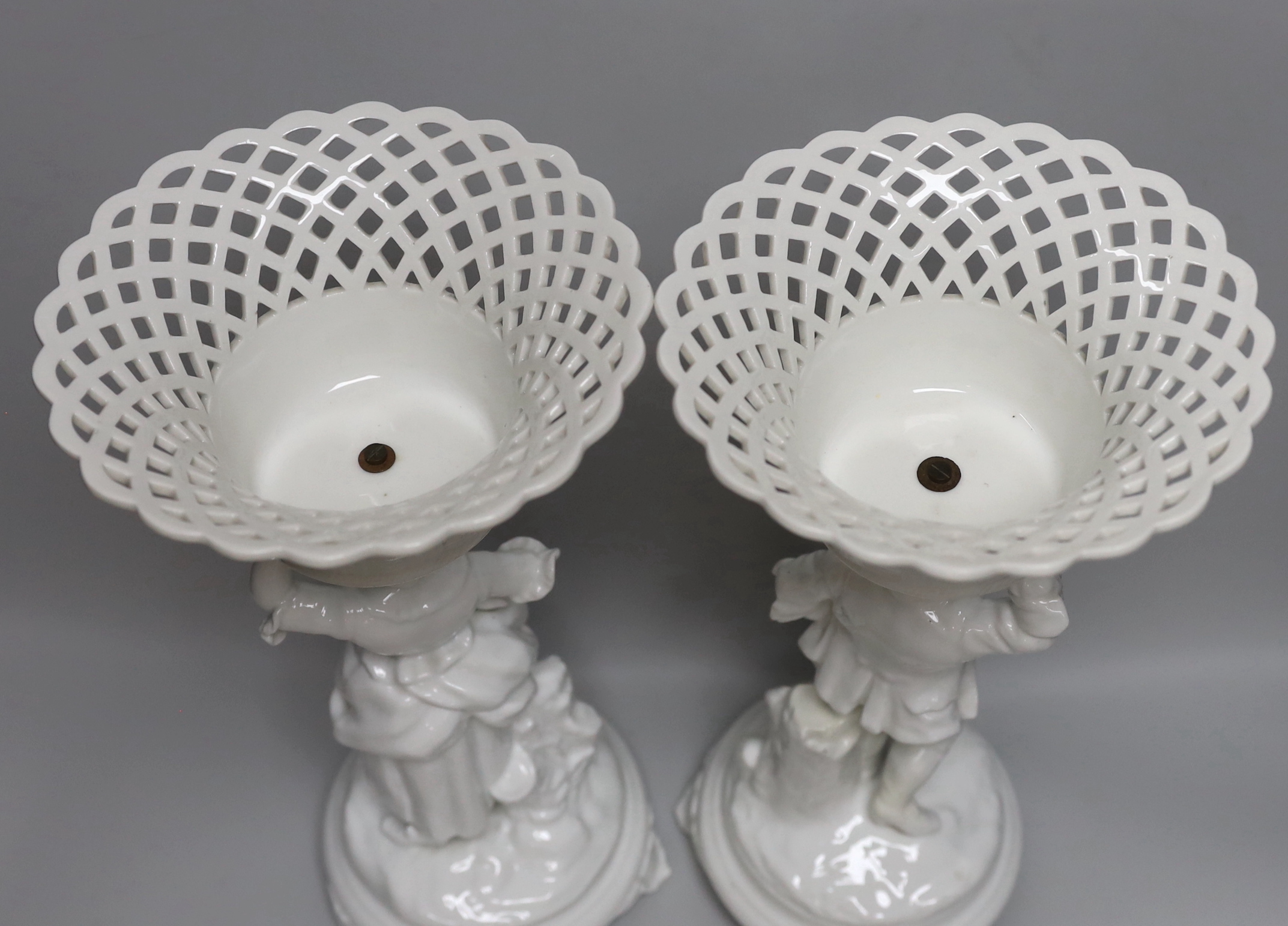 A pair of Paris porcelain figural comports or centre pieces with lattice work baskets, each 38cm high